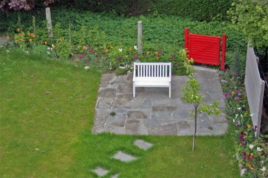 Sitzplatz mit rotem Gartentor und Sichtschutzelemente